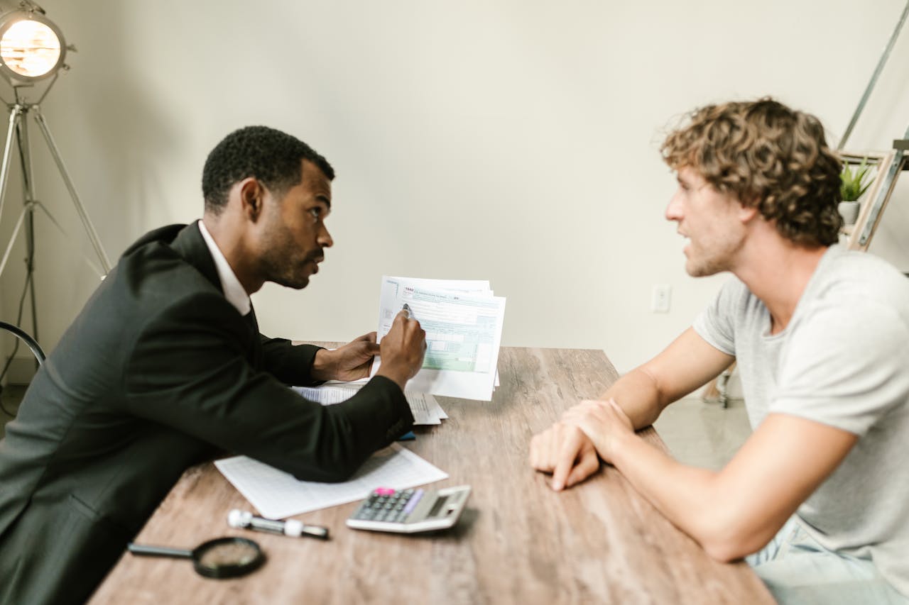 Finance advisor reviewing business loan documents with a client across a desk.