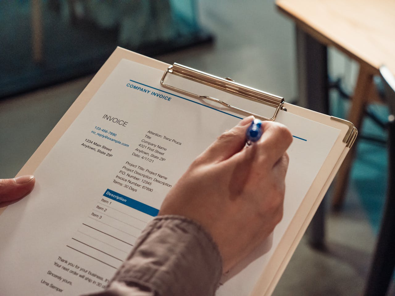 Business professional reviewing a company invoice on a clipboard.